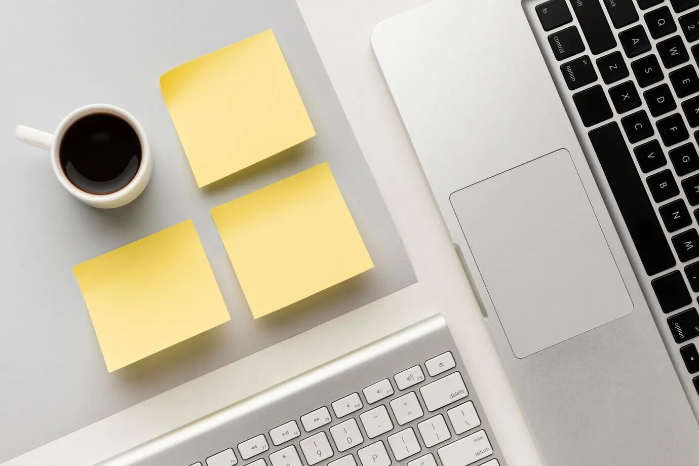 Top-down office desk arrangement with blank sticky notes.