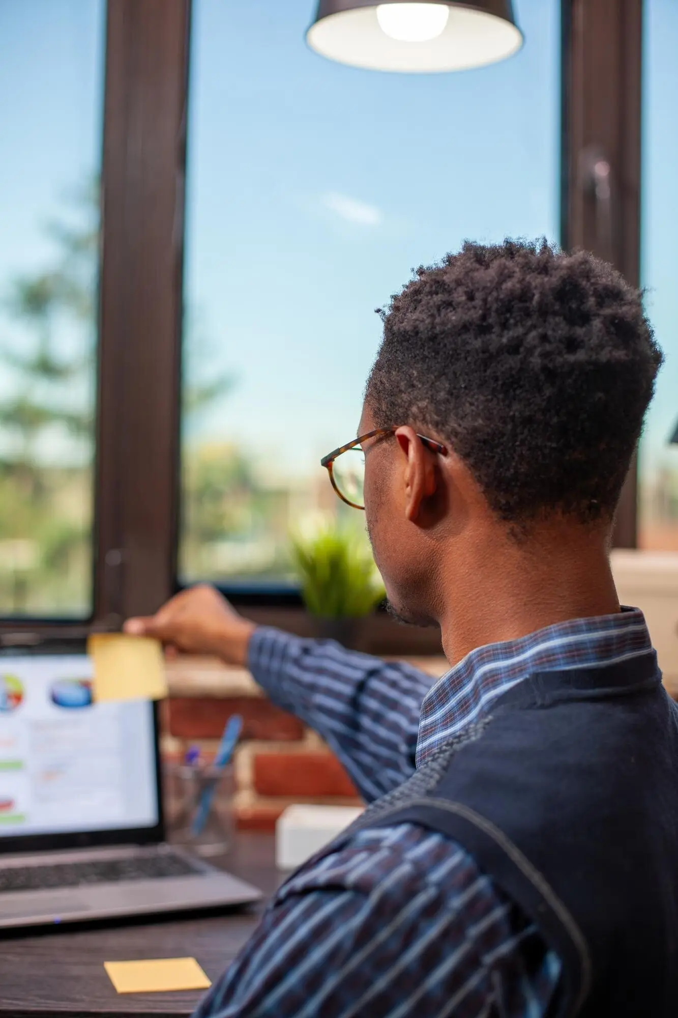 A manager affixes an adhesive note to a laptop.