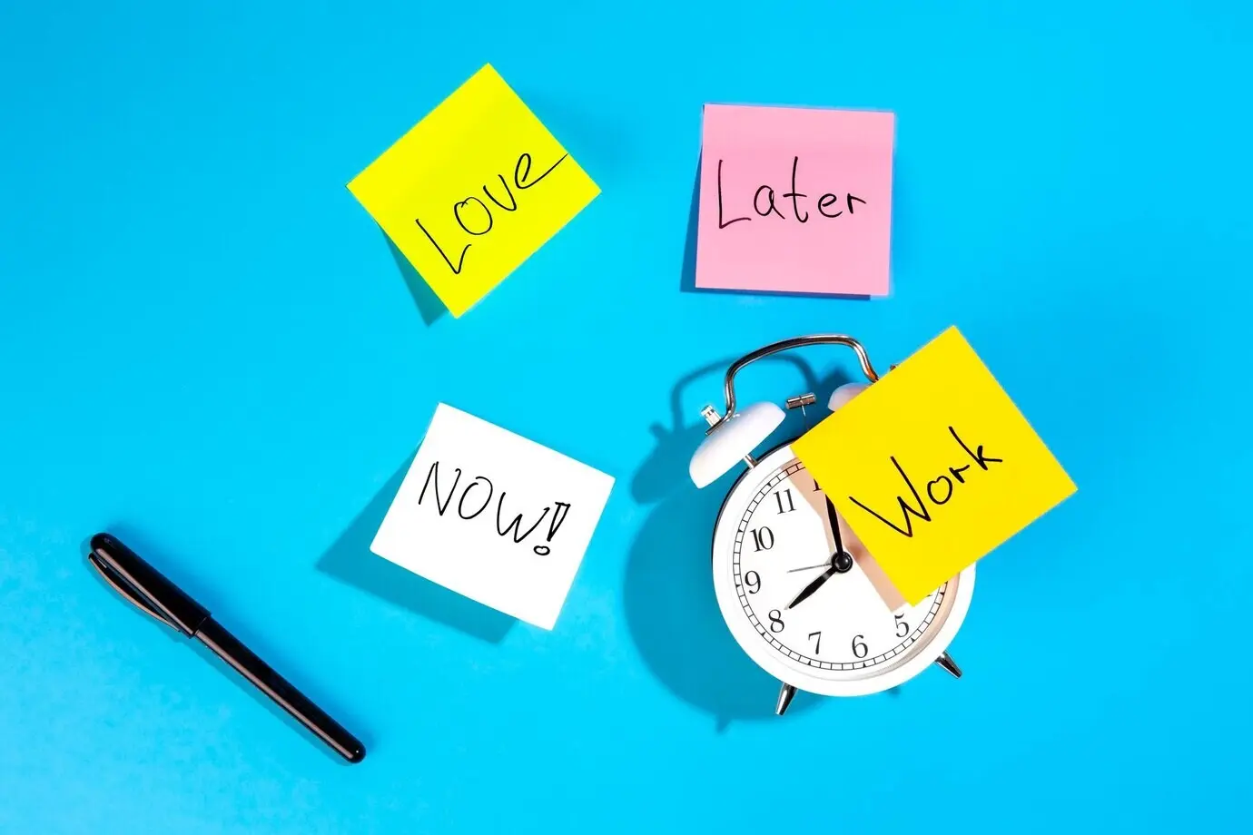 Top view of an alarm clock and colorful paper reminders on a blue background.